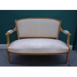 A Louis XVI style gilt framed open arm sofa, with bow seat on tapering fluted supports,