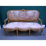 A Louis XV style gilt framed open arm sofa, with triple bow seat on cabriole supports,