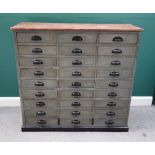 A painted pine bank of three rows of nine drawers, on plinth base, 125cm wide x 119cm high.