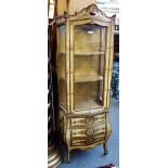 An early 20th century Italian cream painted parcel gilt display cabinet, on bombe three drawer base,