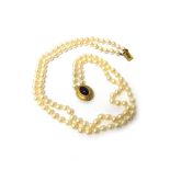 A two row necklace of uniform cultured pearls, on a gold and cabochon amethyst set oval clasp,