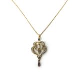 A gold, seed pearl and garnet set pendant in a scrolling and leaf design,