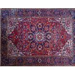 An Heriz carpet, Persian, the madder field with a bold indigo rosette medallion, ivory spandrels,