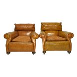 A pair of early 20th century tan leather upholstered deep seat easy armchairs, on bun feet,