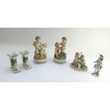 Two Continental porcelain figure groups, each modelled with putti on a circular base, 21.