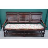 An early 18th century oak triple panel back open arm settle, on block and turned supports,