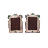 A matched pair of Art Nouveau silver and enamelled shaped rectangular photograph frames,