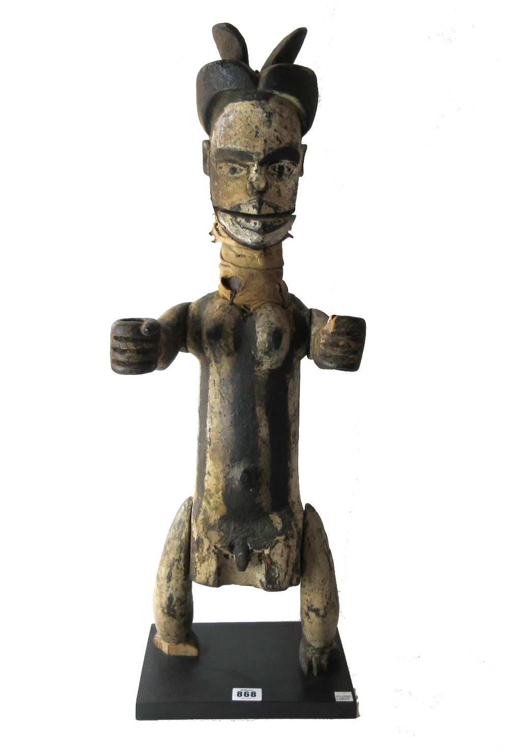 An Ogoni marionette figure, painted carved wood and cloth, on a later ebonised wooden plinth,