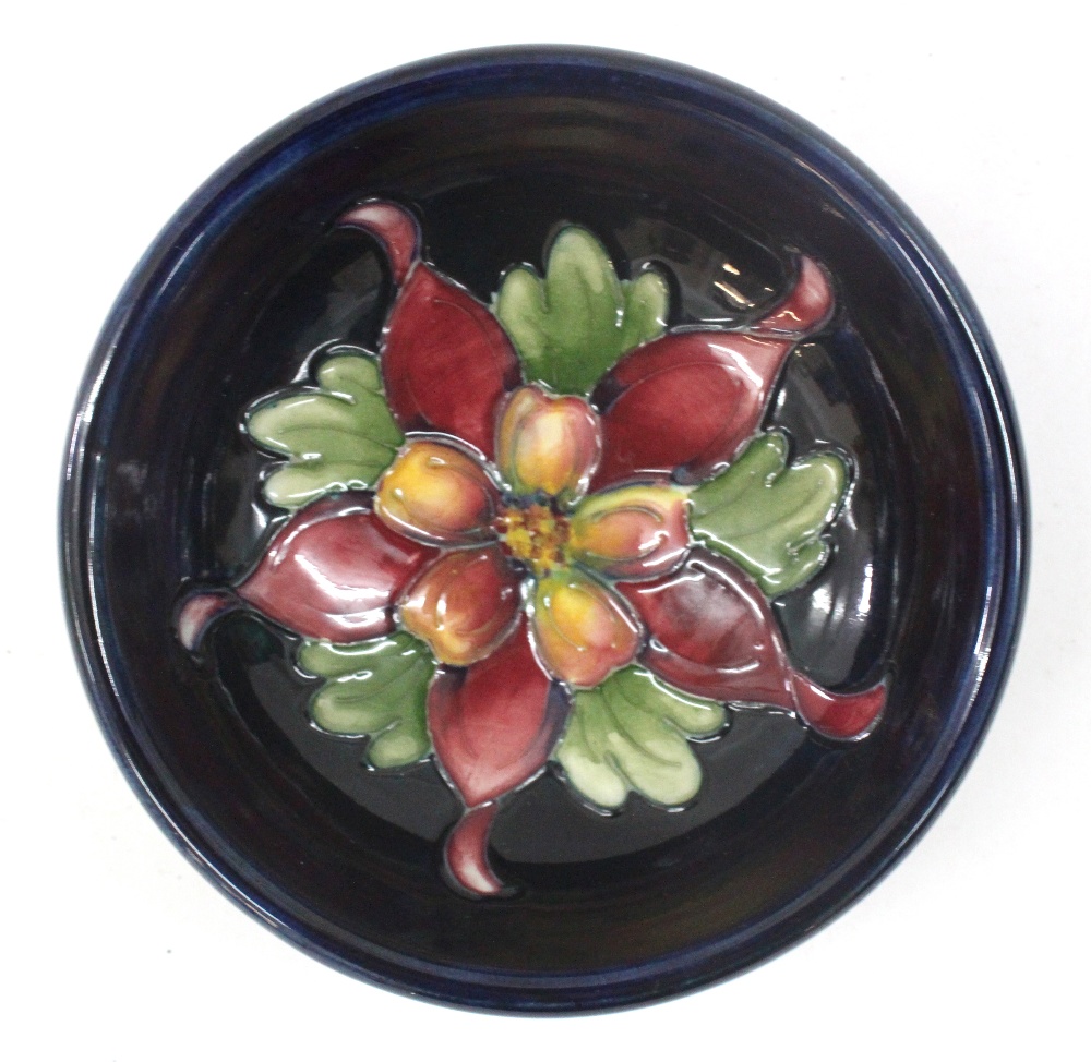 A William Moorcroft Pin Dish with dark blue glaze and tube lined floral decoration, impressed mark.