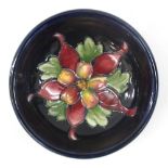A William Moorcroft Pin Dish with dark blue glaze and tube lined floral decoration, impressed mark.
