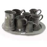 An oval pewter meat dish, with London touch marks, 46cm wide and a collection of seven pewter mugs,