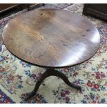 A George III oak tea table, the circular tilt-top on a turned and ringed pillar and tripod base,