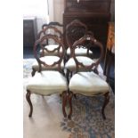 A set of four Victorian carved walnut balloon back dining chairs, with upholstered stuff-over seats,