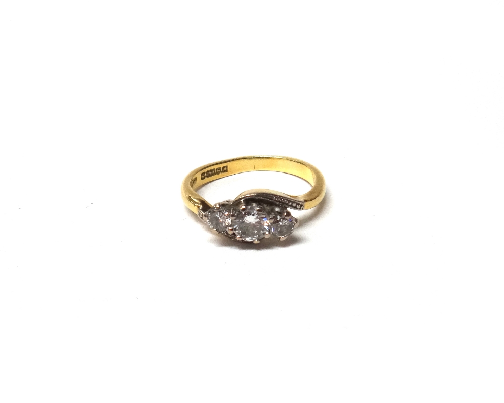 An 18ct gold and diamond set three stone ring, claw set with a row of circular cut diamonds,