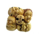 A Japanese ivory netsuke, early 20th century, carved as a group of nine noh masks, signed, 4.5cm.