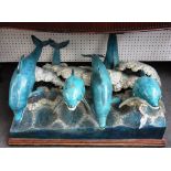 A modern polychrome bronze sculpture, cast with six dolphins jumping through cresting waves,