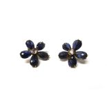 A pair of gold mounted diamond and iolite earclips, each designed as a five petal flowerhead,