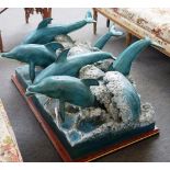 A modern polychrome bronze sculpture, cast with six dolphins jumping through cresting waves,