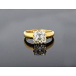 A gold and diamond set single stone ring, claw set with a cushion shaped diamond,