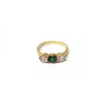A gold, diamond and green gem set three stone ring,