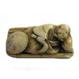 A Japanese ivory netsuke, 18th/19th century, depicting a figure lying on a bed of bamboo canes, 5cm.