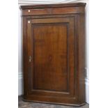 A George III oak and mahogany wall hanging corner cabinet, fitted with shaped shelves,