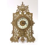 A Victorian brass framed timepiece, the dial surmounted by a lyre and a winged face below,