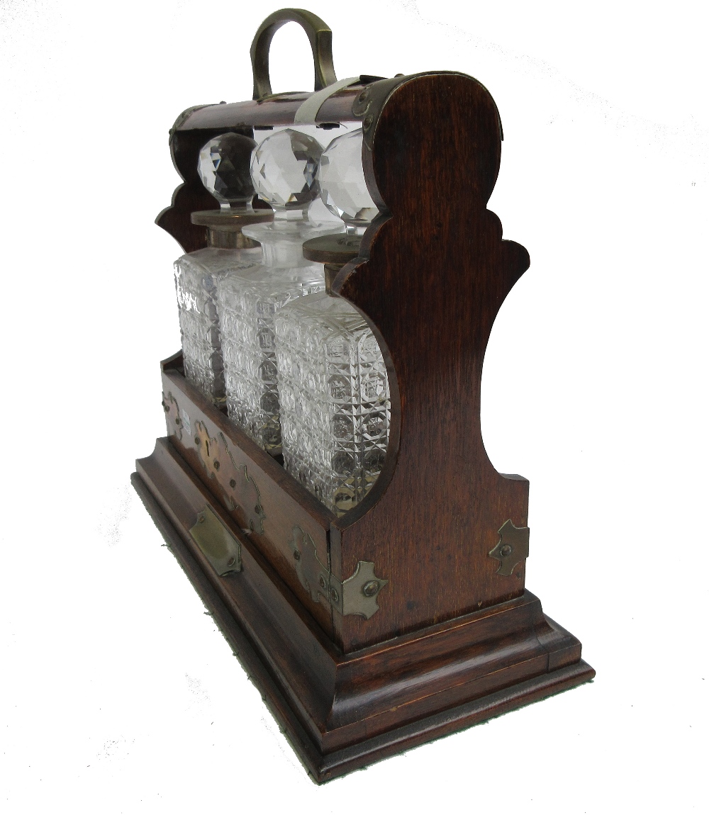 A Victorian brass mounted oak three bottle tantalus, 39cm wide x 36cm high. - Image 2 of 2