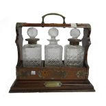 A Victorian brass mounted oak three bottle tantalus, 39cm wide x 36cm high.