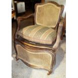 An 18th century French bergere oak framed commode chair, with serpentine seat,