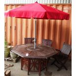 A 20th century stained hardwood octagonal garden table and six folding chairs with cushions,