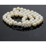 A single row cultured pearl necklace on a diamond clasp, the 57 round cultured pearls approx. 6.
