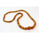 An amber single row necklace, the 59 oval vary coloured 'butterscotch' beads graduated approx. 2.