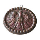 A copper cake mould, early 20th century, with an eagle crest, fluted sides, with hanging ring,