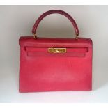 Hermes: Red 28cm 'Kelly' bag with gold plated hardware. Date 1997, lacking padlock and key.