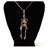 A modern pendant in the form of an articulated skeleton with garnet eyes,