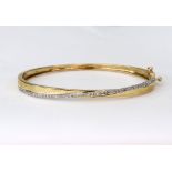 A modern 9ct white and yellow gold and diamond cross-over bangle, the 53 round brilliants approx. 0.