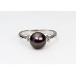 A modern 9ct white gold, black cultured pearl and diamond three stone ring,