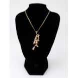 A modern 9ct gold and gem set pendant in the form of an articulated witch on a broomstick,