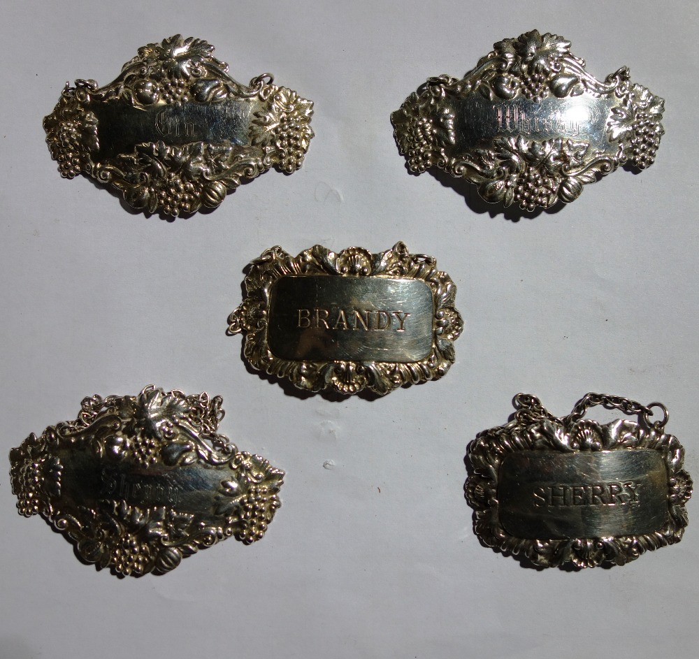 A group of three silver decanter labels, embossed with foliate decoration, detailed Gin,