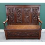 An early 20th century carved oak lift top box seat settle with carved four panel back,