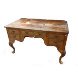 An early 18th century style figural walnut writing desk with five drawers about the arched knee on