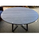 An ebonised oak circular dining table on shaped supports, 137cm wide x 75cm high.