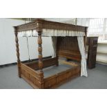 A 17th century style oak four poster bed with panelled canopy and headboard on turned foot board