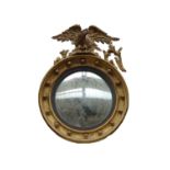 A Regency style gilt framed convex wall mirror, with eagle crest and ebonised slip,