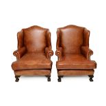 A pair of 18th century style brass studded brown leather upholstered wingback armchairs,