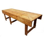 A mid 20th century waxed pine workbench with plank top and block supports, 274cm wide x 87cm high.