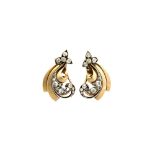 A pair of gold and silver set diamond earclips, each in a scrolled foliate design,