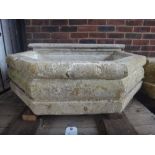 A carved limestone wall fountain, with face mask spout and canted rectangular reservoir,