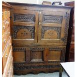 An 18th century carved oak hall cupboard, with pair of doors over three panels and shaped frieze,